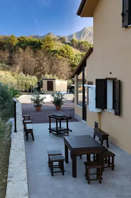 a patio with picnic tables and benches next to a building at Villa Serena - vasca idromassaggio in Borgetto