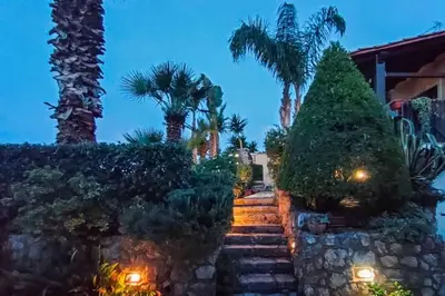 a staircase leading to a house with palm trees and lights at Villa Sterlizia in Castellammare del Golfo
