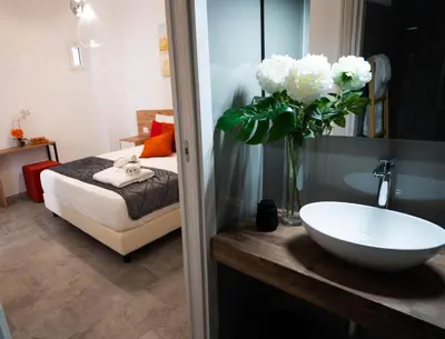 a bathroom with a sink and a bed and a vase of flowers at Le Stanze del Duomo in Partinico