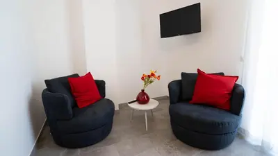a living room with two chairs and a vase with red pillows at Le Stanze del Duomo in Partinico