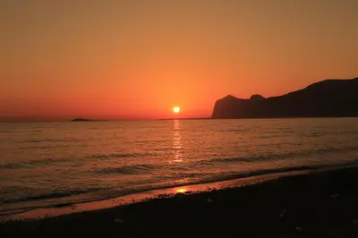 a sunset on the beach with the sun setting at Lido Azzurro Sea Apartments in Carini
