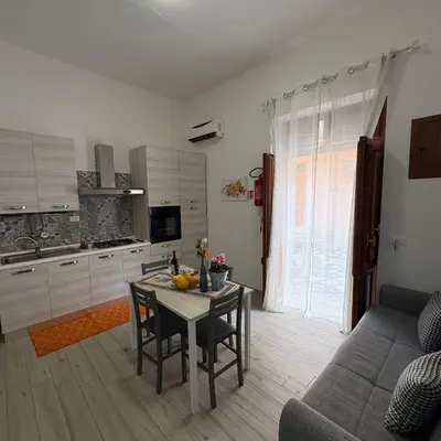 a kitchen and living room with a table and a couch at appartamento gioioso in Castellammare del Golfo