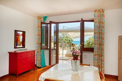 a dining room with a table and a vase of flowers at Villa Azzurra a pochi passi dal mare in Castellammare del Golfo