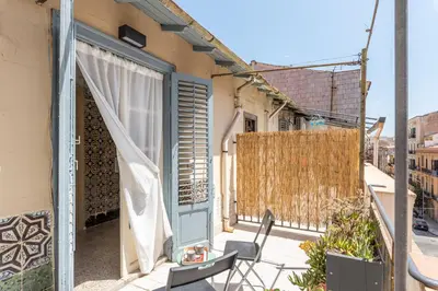 a balcony with a blue door and a table and chairs at Casa Beatrice con Terrazza by Wonderful Italy in Palermo
