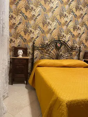 a bedroom with a bed with a yellow bedspread and wallpaper at Appartamento Gelsomino in San Vito lo Capo