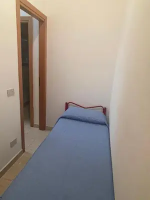 a small bedroom with a blue bed in the corner at Appartamento Giglio in San Vito lo Capo