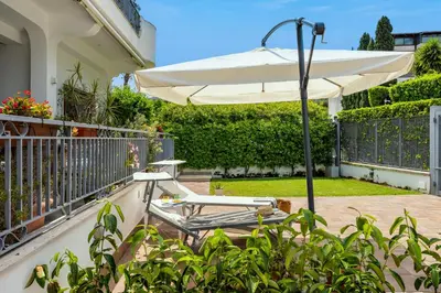 a patio with an umbrella and a chair at More Holidays Beach in Mondello