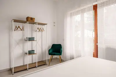a bedroom with a bed and a green chair at More Holidays Beach in Mondello