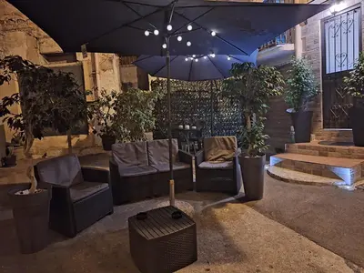 a patio with chairs and an umbrella and plants at La Casetta di Lussy in Palermo