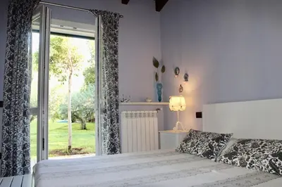 a bedroom with a bed and a large window at Villa Enza Bellissima villa con piscina in Terrasini