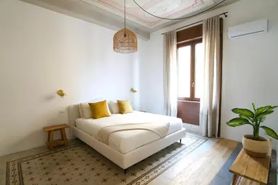 a white bedroom with a bed and a potted plant at Casa Disìu in Palermo
