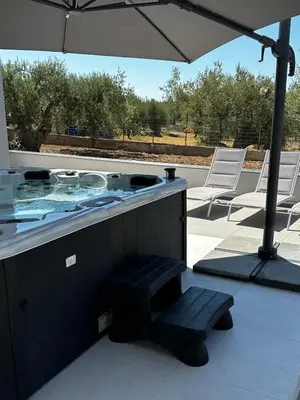 a hot tub with a bench and an umbrella at Villa Valentina in Altavilla Milicia