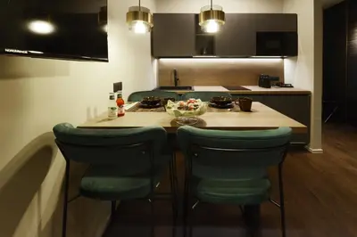a kitchen with a table with green chairs and a counter at Di fronte a Suite in Palermo
