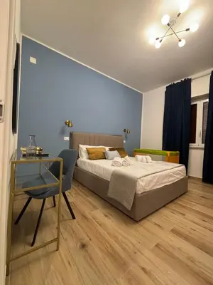 a bedroom with a bed and a table and a chair at La Zisa Luxury Apartment in Palermo