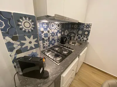 a small kitchen with a stove and tiles on the wall at La Zisa Luxury Apartment in Palermo