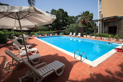 a swimming pool with lounge chairs and an umbrella at Hotel Conchiglia d'Oro in Mondello