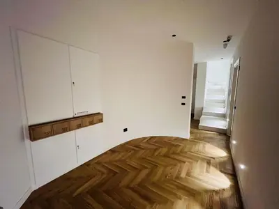 a kitchen with white cabinets and a wooden floor at Marina Boutique Rooms in Carini