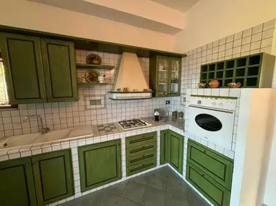 a kitchen with green cabinets and a sink and a stove at Maison Lume in Castellammare del Golfo