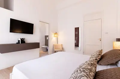 a white bedroom with a bed and a tv at Diletti Rooms in Palermo