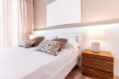 a bedroom with a white bed and a night stand at Diletti Rooms in Palermo