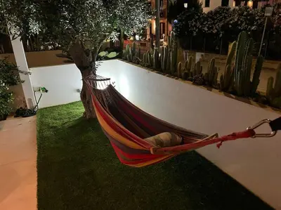 a hammock hanging on a wall next to a tree at Villa Ippolita - 2 Bedrooms Apartment with Exclusive Garden in San Vito lo Capo