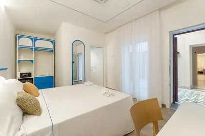 a white bedroom with a large bed and a chair at B&B La Dimora di Poseidone in Bagheria
