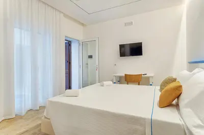 a white bedroom with a large bed and a tv at B&B La Dimora di Poseidone in Bagheria