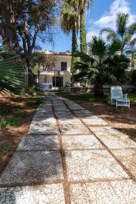 a walkway in front of a house with palm trees at Casa cancello a mare in Santa Flavia
