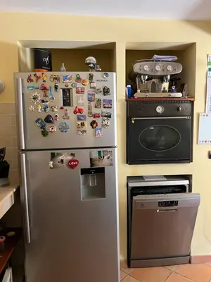 a refrigerator with magnets and a stove in a kitchen at Villa Giovina Mondello in Mondello
