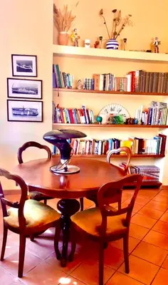a wooden table and chairs in a room with books at Villa Giovina Mondello in Mondello