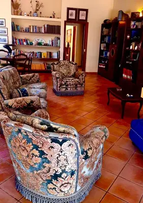 a living room with two chairs and a book shelf at Villa Giovina Mondello in Mondello