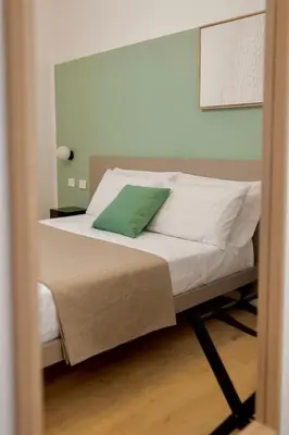 a bedroom with a bed with a green pillow on it at Politeama Charming Apartment in Palermo