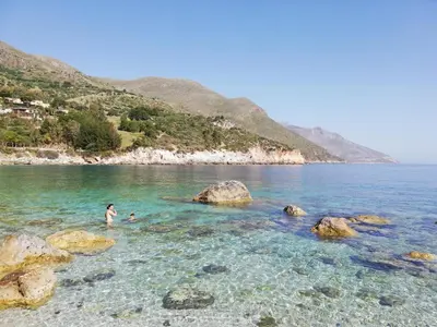 a beach with rocks in the water at Where The Sun Rises in Scopello