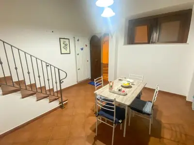 a dining room with a table and chairs and a staircase at La discesa di San Giuseppe in Termini Imerese