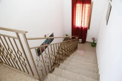 a staircase in a house with a wooden railing at Villa Giù, indipendent villa near airport and sea in Cinisi