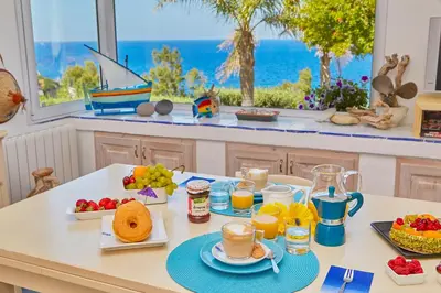 a breakfast table with a view of the ocean at Villa Ginestra - Scopello-Villas in Scopello