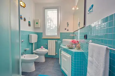 a blue tiled bathroom with a toilet and a sink at Villa Ginestra - Scopello-Villas in Scopello