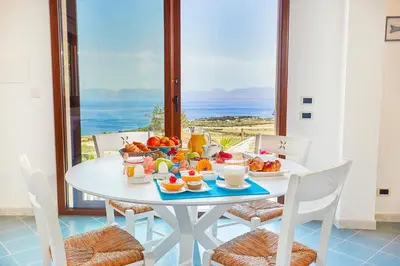 a table with food on it with a view of the ocean at Villa Brezza Marina - Scopello-Villas in Scopello