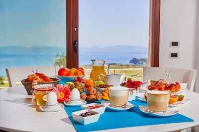 a table with a breakfast of fruit and coffee at Villa Brezza Marina - Scopello-Villas in Scopello