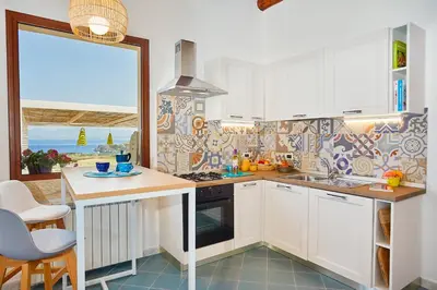 a kitchen with white cabinets and a sink and a counter at Villa Brezza Marina - Scopello-Villas in Scopello