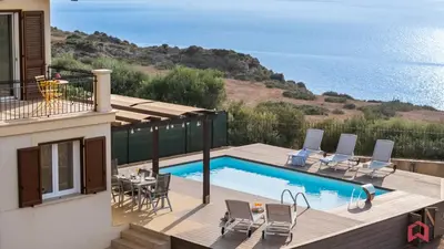 a swimming pool with chairs and a table and the ocean at Villa with Sea view Private Pool in Terrasini