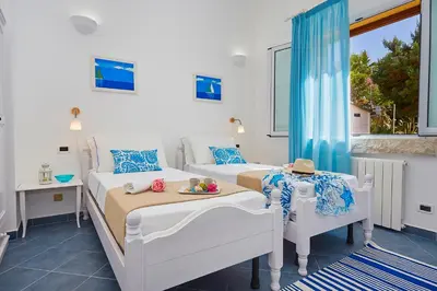 a bedroom with two beds and two tables and a window at Villa Desirée - Scopello-Villas in Scopello