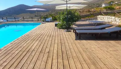 a pool with benches and umbrellas on a wooden deck at Il Casale San Vito in San Vito lo Capo
