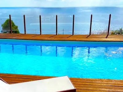 a swimming pool with blue water and wooden pier at Il Casale San Vito in San Vito lo Capo