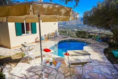 a pool with an umbrella and chairs and a table at Villa Rosa Dei Venti - Scopello-Villas in Scopello