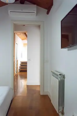 a room with a bed and a television and a hallway at Vittorio Emanuele Suite Apartment in Palermo