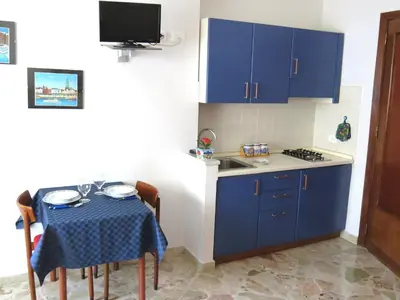 a small kitchen with blue cabinets and a table at Appartamento Blu in Palermo