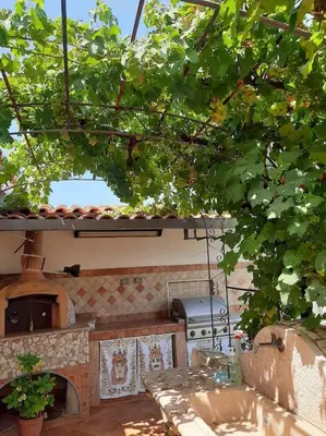 an outdoor kitchen with a table and a pizza oven at Casa Vacanze Anthea Carini in Carini
