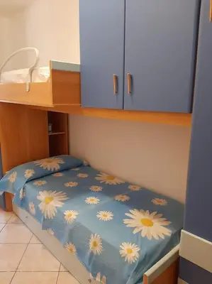 a bed with a blue blanket with daisies on it at Casa Vacanze Anthea Carini in Carini