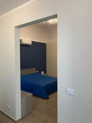 a bedroom with a blue bed and a white wall at B&B Garibaldi in Palermo